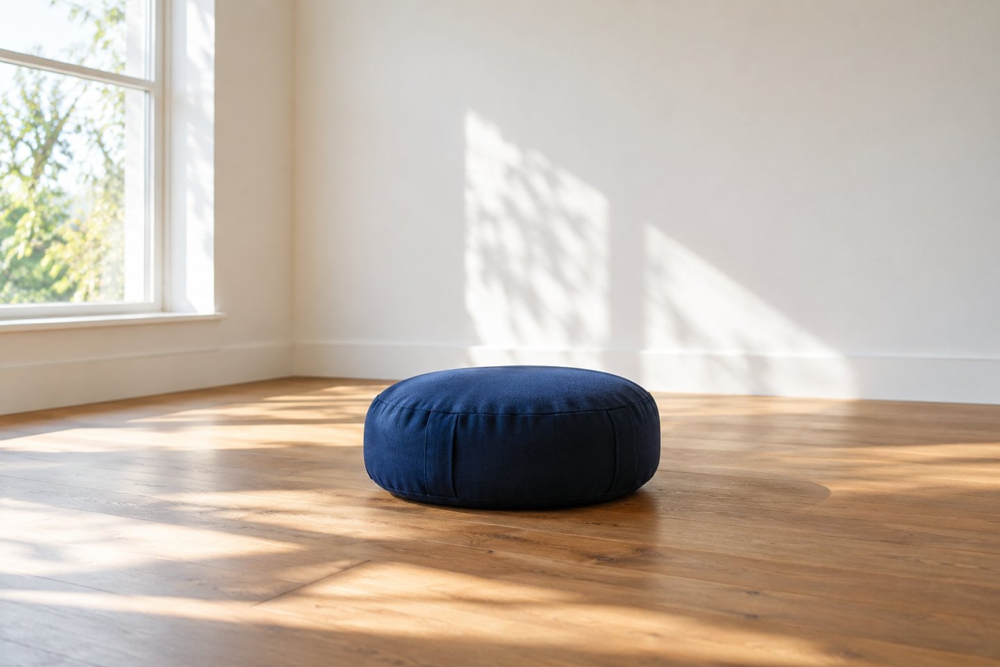 Meditation cushion in an empty sunlit room.